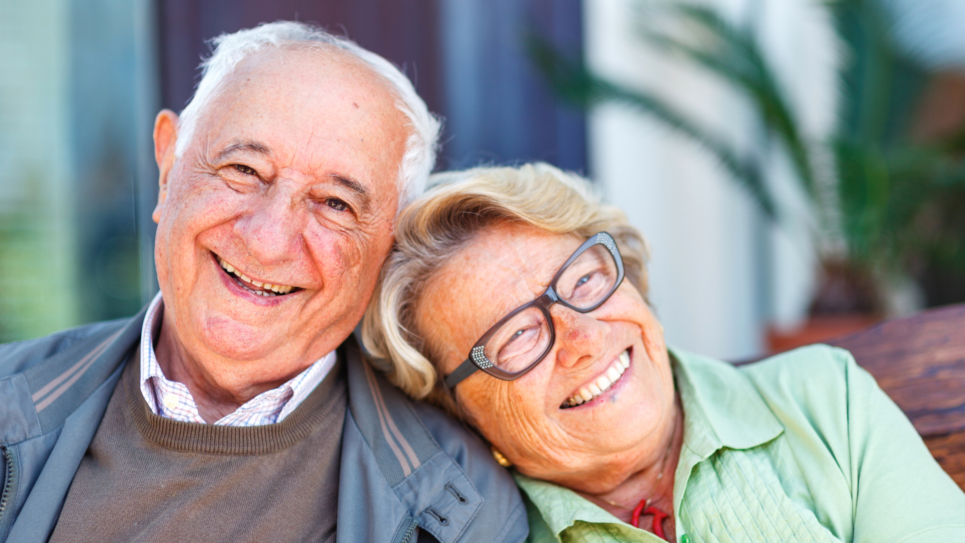 Photo of male smiling towards camera with female smiling away from camera and leaning on male's shoulder