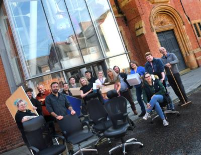 Image of a group of staff standing in front of the Pyramid with boxes and chairs. They are moving out of the building for its refurbishment.