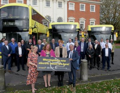 Image of more than 30 guests at Warrington Town Hall, standing in front of three new electric buses, two single deckers and one double deckers.