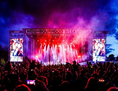 Night time image of a crowd at the Neighbourhood Weekender festival, Victoria Park, watching a band perform from a lit stage.