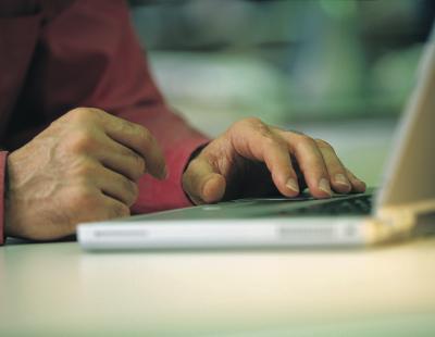 Close-up image of hands using a laptop.